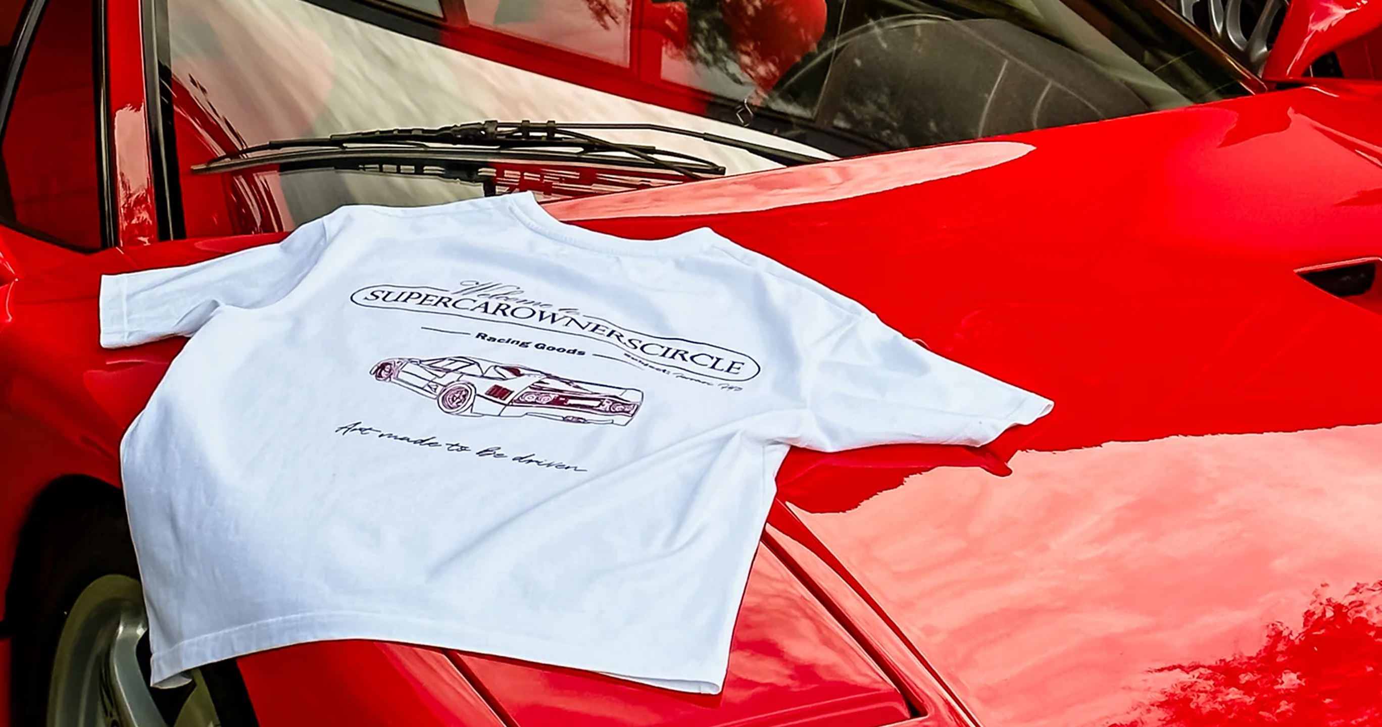 White t-shirt with 'Supercarownerscircle' logo on a red car